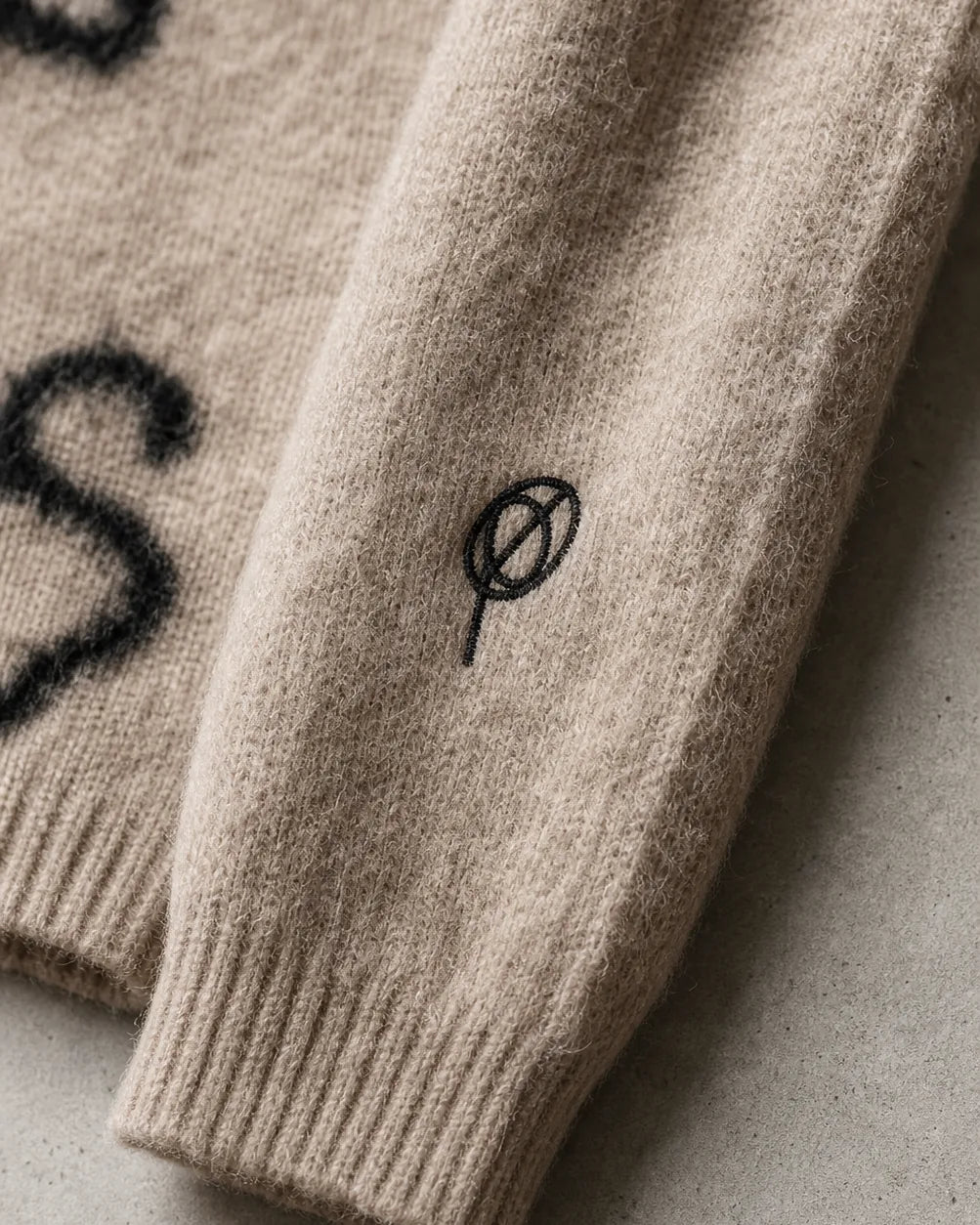 Mohair Sweater — close-up of the black ∅ sleeve logo embroidery